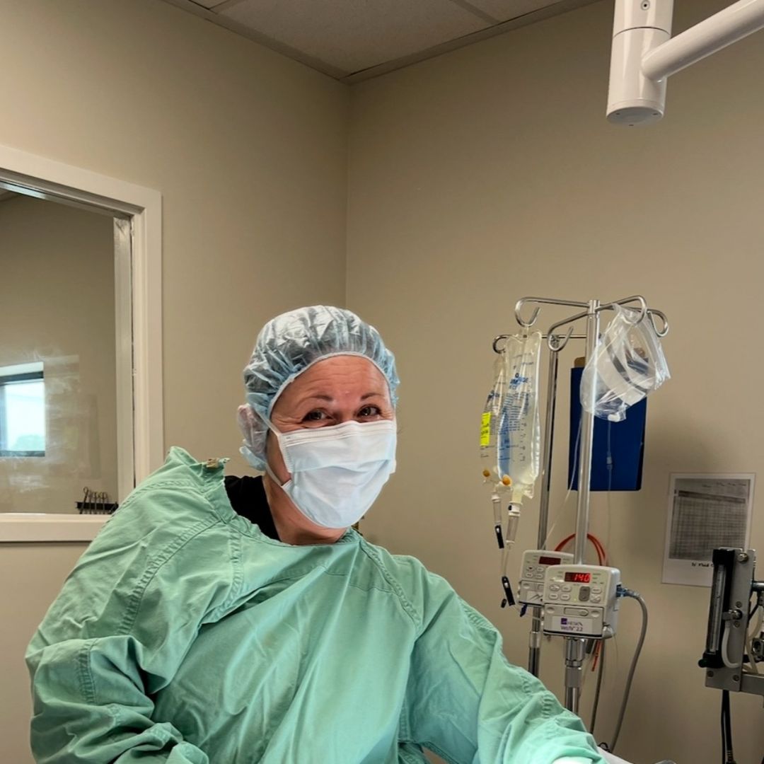 Front Desk Smiles with Clinic Cat Team member at Cashua Veterinary Care smiling and holding an orange cat at the front desk while another staff member works in the background.
